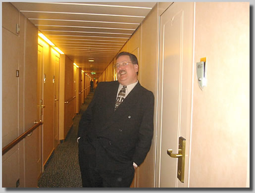 Dennis posing in front of the long hallway that led to the cabins on deck 4 where our cabin was. This was on the way up to the formal dinner where I proposed to her. I was a pretty happy guy just then, a bit nervous, but very happy.