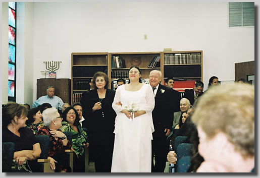 This is the wedding Processional with Rooty Jr. beaming as she is escorted in by Fortuna and Isaac, her parents.